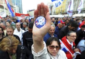 A woman shows off a badge with a picture of Croatia's general Ante Gotovina during an anti-government rally at the Zagreb main square